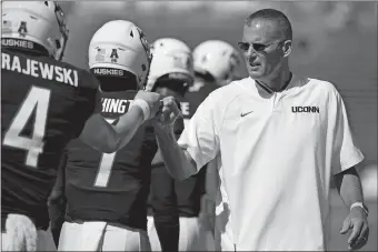  ?? JESSICA HILL/AP PHOTO ?? UConn head coach Randy Edsall bumps fists with reserve quarterbac­k Steven Krajewski during warmups prior to last Saturday’s 56-49 win over Rhode Island at Rentschler Field in East Hartford. Edsall returns to his alma mater, Syracuse, to face the unbeaten Orange today at the Carrier Dome.