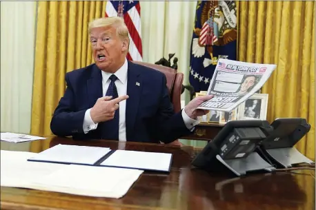  ?? EVAN VUCCI — THE ASSOCIATED PRESS ?? President Donald Trump holds up a copy of the protection­s for social media giants Thursday. before signing an executive order aimed at curbing