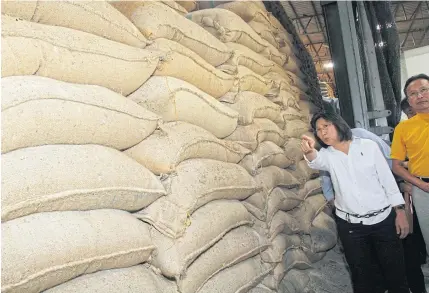  ?? TAWATCHAI KEMGUMNERD ?? Mrs Duangporn inspects pledged rice being stored at a warehouse in Nakhon Pathom province. State-held rice stocks have recently fallen to 5.04 million tonnes.