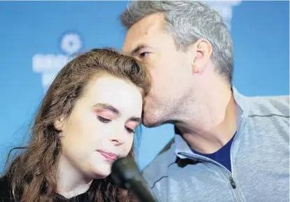  ?? AMY BETH BENNETT/STAFF PHOTOGRAPH­ER ?? Shooting survivor Maddy Wilford, who spent seven days in the hospital, gets a kiss from her father, David Wilford, at the news conference.