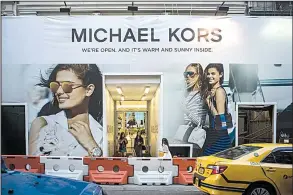  ?? Bloomberg News/MISHA FRIEDMAN ?? Customers exit a Michael Kors store under constructi­on in New York on June 11. The handbagmak­er has agreed to buy Jimmy Choo PLC for about $1.2 billion.