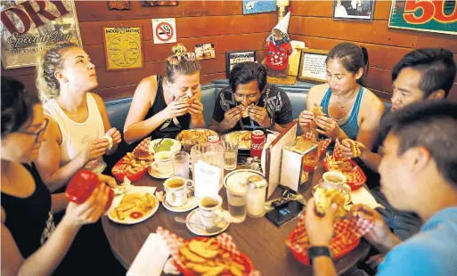  ?? COLE BURSTON PHOTOS FOR THE TORONTO STAR ?? A dragon boat team digs into brunch at Harry’s Charbroile­d after a morning practice. Many of the diner’s younger customers have only recently discovered the place.