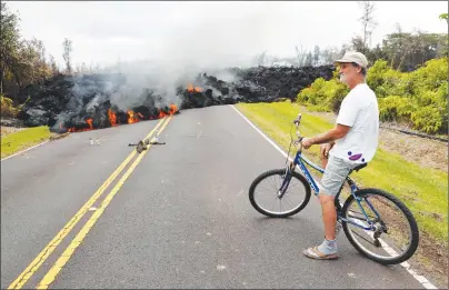  ?? AP PHOTO ?? Leilani Estates resident Sam Knox watches the lava stretch across the road, Saturday in Pahoa, Hawaii. Knox’s home is less than a few hundred yards from the lava flow and he does not have any plans to evacuate.