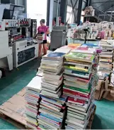  ??  ?? Une employée protège les livres d’occasion avec du film plastique.