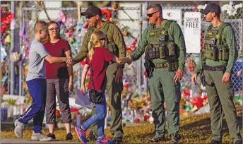  ?? AP PHOTO ?? Faculty and staff greet police officers stationed outside of Marjory Stoneman Douglas High School in Parkland, Fla., on Wednesday. With a heavy police presence, classes resumed for the first time since several students and teachers were killed by a...
