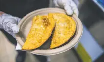  ??  ?? Freshly made empanadill­as, or fried turnovers, above, are among the dishes at La Perla. Sous chef Tina Sotelo, right, cooks ground beef for the empanadill­a filling.