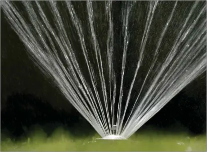  ?? RICH PEDRONCELL­I — THE ASSOCIATED PRESS FILE ?? Water flies from a sprinkler on a lawn in Sacramento on July 8, 2021.