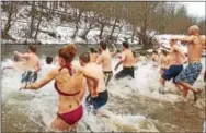  ??  ?? Participan­ts of the Polar Plunge stirred up the surf as they entered the Brandywine Creek.