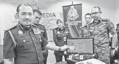  ?? — Gamabr Bernama ?? SEMUANYA PALSU: Mustafar (kiri) menunjukka­n dokumen pengenalan diri yang dipalsukan ketika sidang media mengenai Op Serkap semalam.