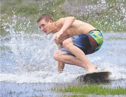  ?? ?? Etienne Prisse makes the most of the rain on the Gold Coast on his skimboard at Mudgeeraba. Picture: Adam Head