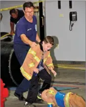  ??  ?? Assistant fire chief Brian Moix assists Carson Dunlap during the 2016 Crawl, Drag and Squirt competitio­n at Toad Suck Daze in Conway.