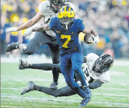  ?? Michael Conroy The Associated Press ?? Michigan running back Donovan Edwards leaves Purdue safety Sanoussi Kane (21) in his wake during the Wolverines’ 43-22 victory Saturday at Lucas Oil Stadium. Edwards ran for 185 yards and a TD.