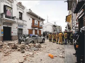  ?? Xavier Caivinagua Associated Press ?? RESCUE WORKERS gather Saturday in Cuenca, Ecuador, following a magnitude 6.8 earthquake. An architect said many homes that collapsed were built from adobe and deficient in structural and technical design.