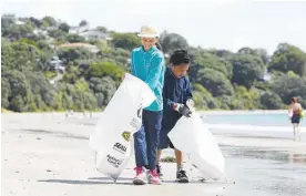  ?? Photo / Chris Gorman ?? Mercy Kiddie (left), 10, and Sam Tuimauga, 9, help to clean up rubbish left or washed up at Oneroa Beach on Waiheke Island.