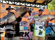  ?? (Photo courtesy of VisitHelen­aAr.com) ?? Chad Bailey (left) of Florida and Aaron Churchill of Georgia weigh in their catfish during the Catmasters tournament Friday.