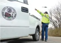  ??  ?? City of Whitwell employee Jeffrey Hundley directs traffic onto South Magnolia Street from State Highway 283 as a Georgia State Patrol helicopter hovers overhead during Tuesday’s manhunt.