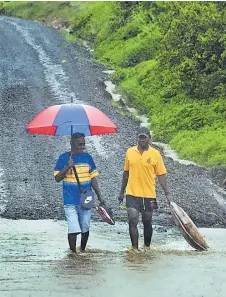  ?? Picture: ELIKI NUKUTABU ?? Qelekuro villagers Sevanaia Tauvoli (left) and Veniasi Saqa cross a flooded portion of road to get to their farm in Dawasamu, Tailevu North yesterday.