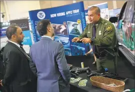  ?? John Moore Getty Images ?? A RECRUITER with Border Patrol speaks to attendees of the Border Security Expo in 2017 in Texas. Strict vetting requiremen­ts make the hiring process slow.