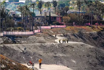  ?? ?? Firefighte­rs and residents stand Thursday on a fire road where the Coastal Fire jumped and burned several homes in Laguna Niguel.