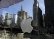  ?? KIICHIRO SATO — THE ASSOCIATED PRESS FILE ?? Buildings and a tour boat are reflected on the mirror behind an Apple logo during a preview event at a new Apple Michigan Avenue store in downtown Chicago.