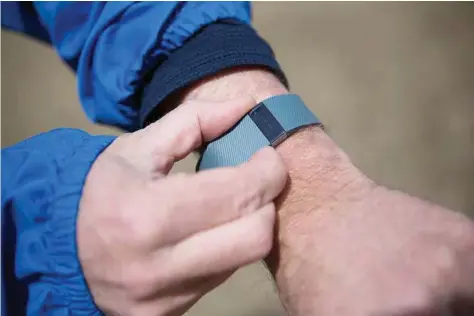  ?? Charlie Mahoney / The New York Times ?? Michael Doughty sets his Fitbit wristband prior to a run in Boston. A new study shows dieting adults who wore activity monitors for 18 months lost significan­tly fewer pounds over that time than those who did not.