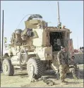  ?? KHALID MOHAMMED / AP ?? U.S. soldiers stand outside their armored vehicle south of Mosul, Iraq, in February. As Iraqi forces push into western Mosul, coalition troops are closer to frontline fighting than ever before.