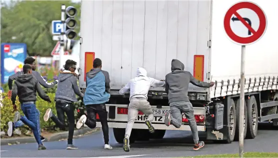  ?? (AFP) ?? Migrants attempt to open the rear door of a truck at the Brittany ferry port in Ouistreham, northweste­rn France, on Tuesday