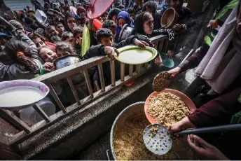  ?? Gaza”. — AFP photo ?? Displaced Palestinia­n children gather to receive food at a government school in Rafah. Save the Children says the ris�� of famine would continue to “increase as long as the government of Israel continues to impede the entry of aid into
