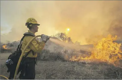  ?? AP PHOTO ?? A firefighte­r battles a wildfire near Placenta Canyon Road in Santa Clarita, Calif. Thousands of homes remained evacuated Sunday as two massive wildfires raged in tinder-dry California hills and canyons.