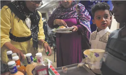  ?? CITIZEN NEWS SERVICE PHOTO BY CHRISTIAN K. LEE ?? Isa Khokhar, 7, in the white button-down shirt, helps serve food after a prayer service at the end of the day.