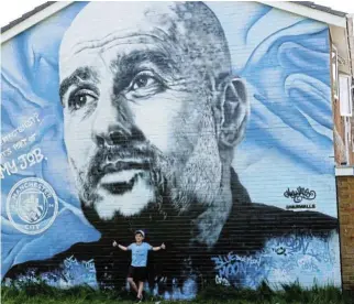  ?? /Reuters ?? Main man in Manchester: A mural of Pep Guardiola is enjoyed by a young Man City fan.