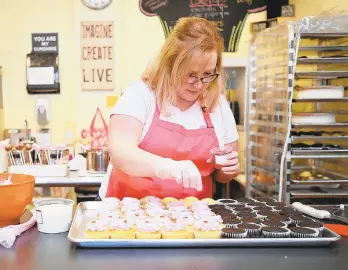  ?? APRIL BARTHOLOME­W/THE MORNING CALL ?? Sweet Girlz Bakery owner Kari Kirchgessn­er decorates vanilla cupcakes with pink icing and little red hearts in 2016. The Easton bakery plans to open a second location at the forthcomin­g Trolley Barn Public Market in Quakertown.