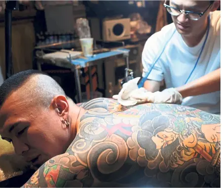  ?? — Photos: AFP ?? Tattoo artist Chen retouching the tattoo on the back of a client in Taipei. A former graffiti artist, Chen, 35, switched to tattooing five years ago after learning the craft in Thailand.