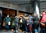  ??  ?? Devant le magasin, la file d’attente ne désemplit pas. Le livreur s’élance hors de la boutique avec sa précieuse marchandis­e.