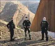  ?? Molly O’Toole Los Angeles Times ?? BORDER PATROL officials Jeff Stephenson, left, Jacob MacIsaac and Gary Richards next to a portion of wall under constructi­on in San Diego County.