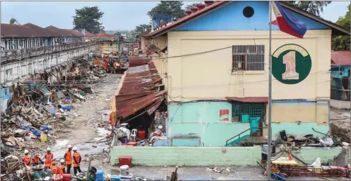  ??  ?? Teams (bottom left) take a break after heavy equipment was used to demolish illegal structures set up and used by inmates inside the maximum security New Bilibid Prison in suburban Manila, yesterday.