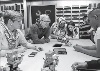  ?? -AFP ?? Tim Cook, CEO of Apple, uses iPad and UBTech Robotics' products to teach young people about programmin­g and robotics technology in an Apple store in Canada.