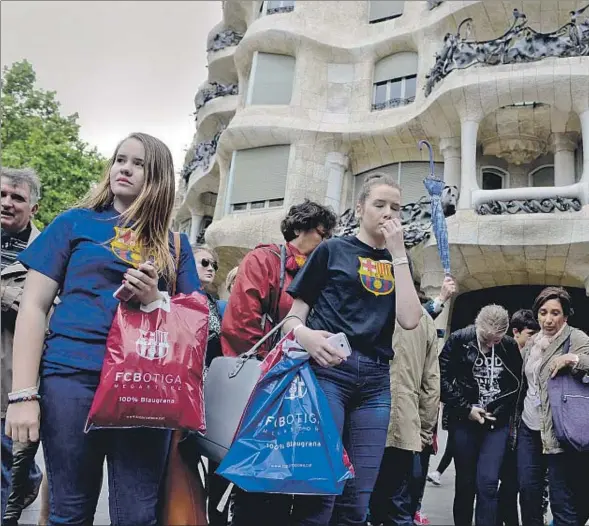  ??  ?? Tras las compras en una de las tiendas oficiales del Barça, un grupo de turistas visita la Pedrera