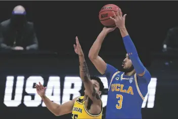  ?? MICHAEL CONROY/AP ?? UCLA GUARD JOHNNY JUZANG (3) shoots over Michigan guard Eli Brooks (left) during the first half of an Elite 8 game in the NCAA men’s tournament at Lucas Oil Stadium on Tuesday in Indianapol­is.