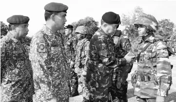  ??  ?? Sittiporn (third left) puts a ‘Toha’ on the arm of a Malaysian soldier after opening the Land Thamal Exercise at the Third Battalion Border Regiment. Also present is Azizan (second left). — Bernama photo