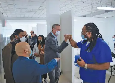  ?? (AP/Kevin Hagen) ?? New York City Mayor Bill de Blasio greets nurse practition­er Alexander Gumbs on Sunday during a visit to a vaccinatio­n facility in the city’s Bronx borough. The facility had previously been used as a covid-19 testing site.