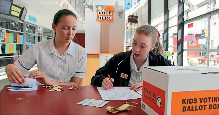  ?? AMY BAKER/STUFF ?? Year nine students Emma Archer-Scott, 14, and Lily Woods, 13, checked ID and gave out voting papers.