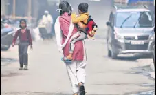  ?? HT FILE ?? A girl holds a child as she returns from school in Noida.