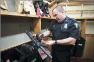  ?? ANDY MORRISON — THE BLADE VIA AP ?? Sgt. Ed Mack looks at a pistol in an evidence room at the Toledo Police Department, in Toledo, Ohio. In the basement of the Toledo Police Department, more than 20,000 items collected from crime scenes across the city each year are stored to help verify what happened or to be used to find and convict suspects.