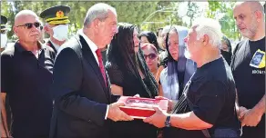  ?? ?? President Ersin Tatar handing over the flags that Orhan Ismail’s coffin was draped in to Yaşar İsmailoğlu