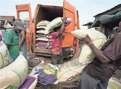  ?? SUNDAY ALAMBA/AP FILE ?? Workers load bags of rice into a truck at a market in Lagos, Nigeria, on Feb. 7. Authoritie­s are struggling to replace Nigeria’s old currency with new notes in the cash-reliant country.