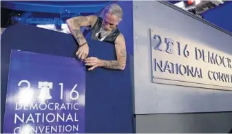  ?? JOHN LOCHER/ASSOCIATED PRESS ?? Gary Gort, a set carpenter with a cable news network, adjusts a sign during preparatio­ns before the 2016 Democratic Convention on Sunday in Philadelph­ia. The convention starts today.