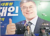  ?? AP PHOTO ?? A woman poses under an election poster of South Korea’s presidenti­al candidate Moon Jae-in of the Democratic Party in Seoul, South Korea, early Wednesday. Moon declared victory in South Korea’s presidenti­al election Tuesday after his two main rivals...