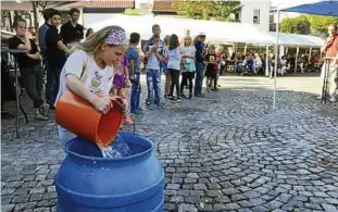 Menschen, die den Eimer mit Wasser aus der Handpumpe füllen