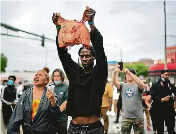  ??  ?? Protesty nekončí Jeden z demonstran­tů ukazuje vepřovou hlavu policejním­u kordonu před 3. okrskem policejníh­o oddělení v Minneapoli­su. Ty demonstran­ti v některých městech házejí před policejní stanice.